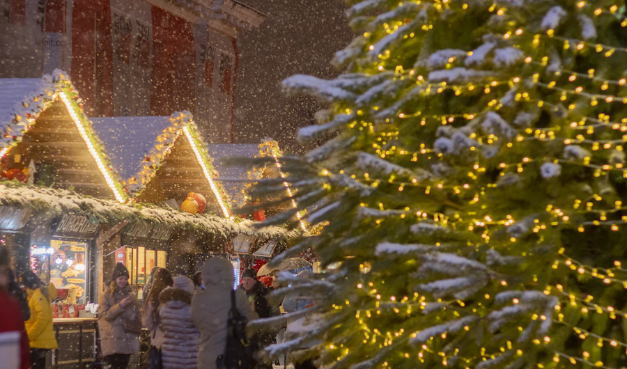 Christmas market stalls and a lit Christmas tree at night