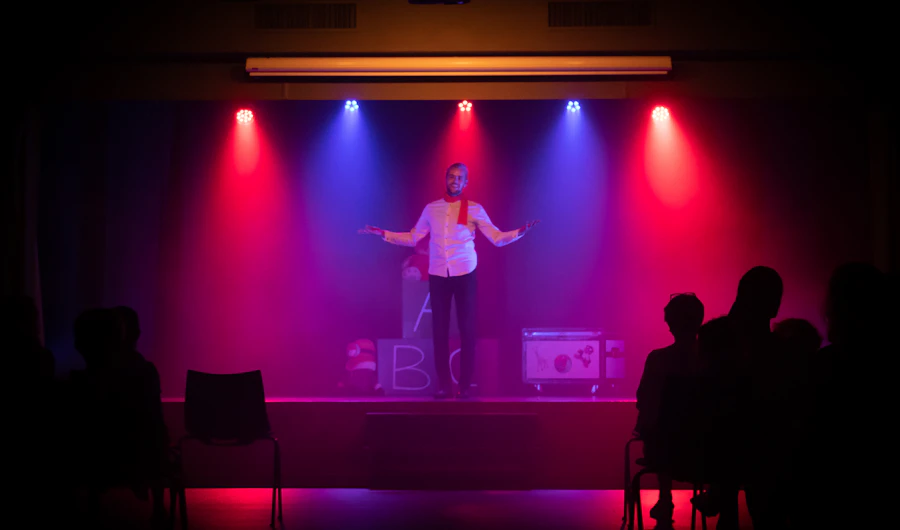 Stand-up comedian with a microphone on a stage lit in purple and red