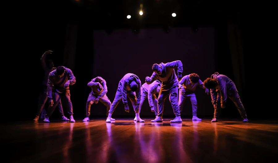 Dance group performing on stage under pink and purple lights