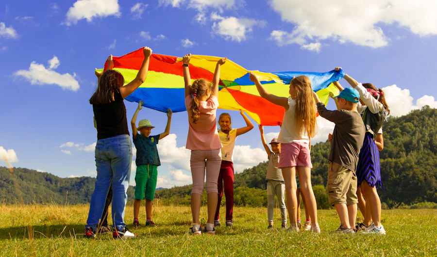 Children playing with a rainbow parachute on the grass