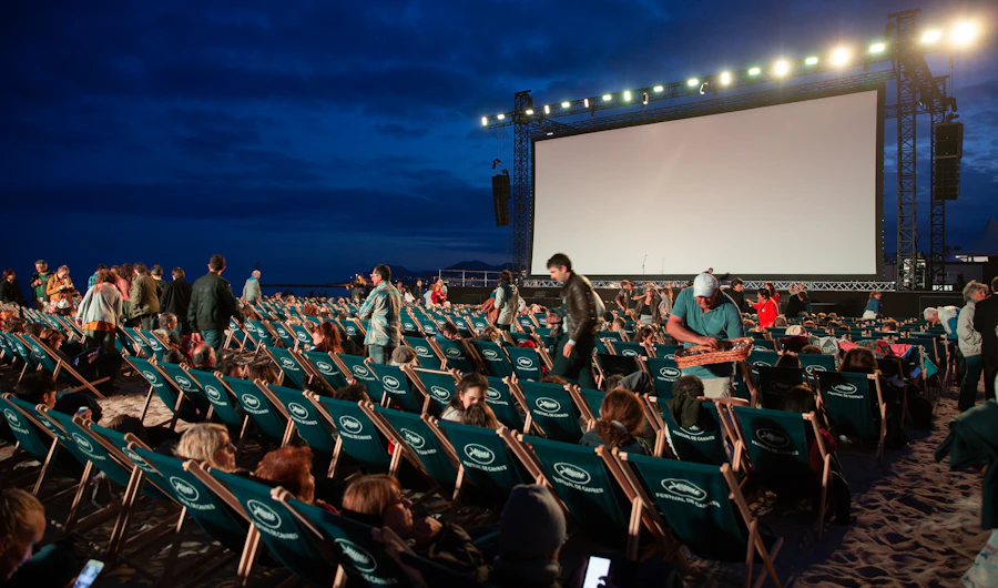 Open-air cinema screen at night with the audience in rows of chairs