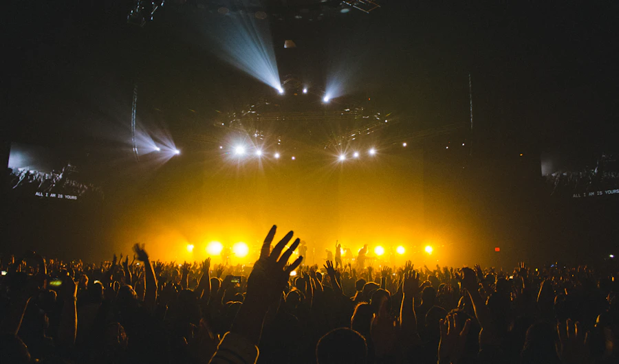 Band playing on a stage in yellow light in front of a concert crowd
