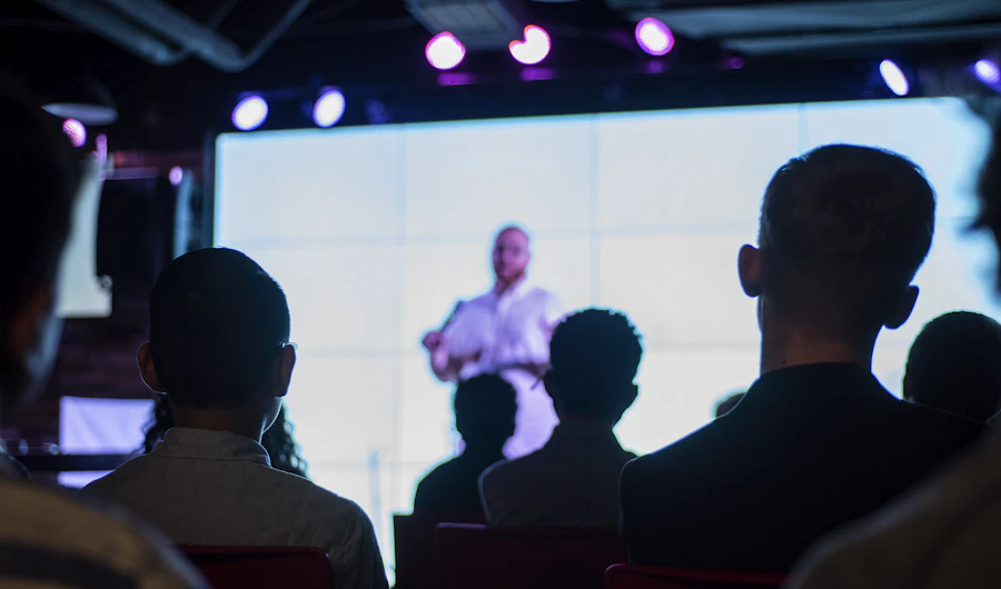 Audience watching a speaker on a bright stage